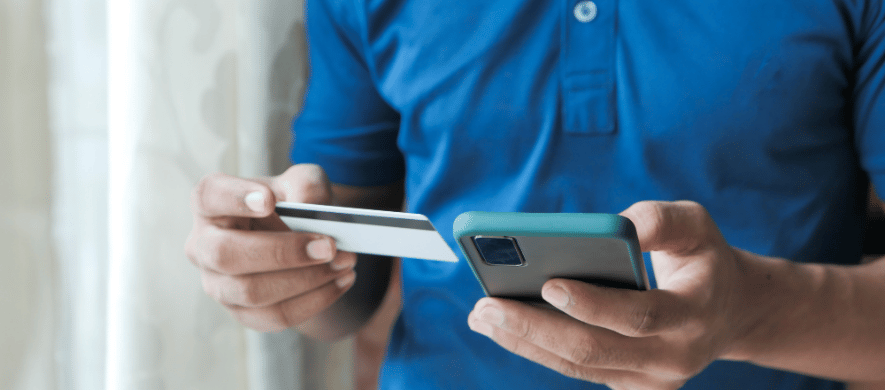 A person holding their credit card in one hand and cellphone in the other, demonstrating digital banking