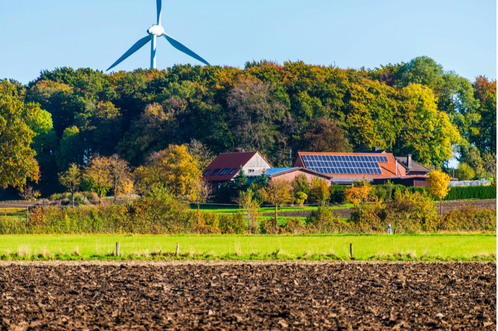 A farm landscape featuring a wind turbine in the background, symbolizing farm renewable energy financing.