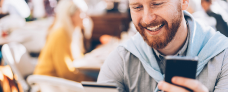 A smiling man with a beard holds a credit card, representing user satisfaction with the Farmers Bank mobile app.