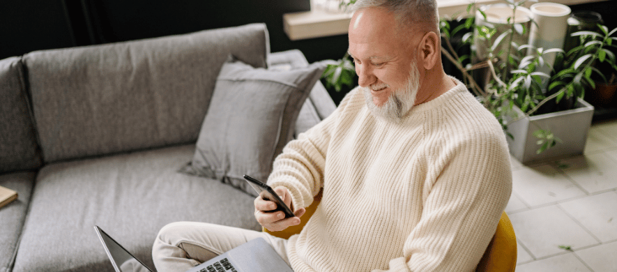 An older man seated with a laptop, focused on learning how to use Zelle for digital payments.