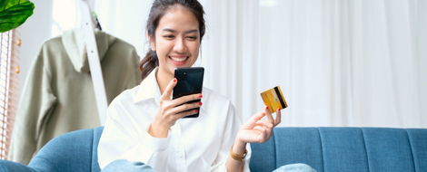 Woman using a smartphone and credit card to make an online purchase, highlighting how to maximize UChoose rewards program benefits.