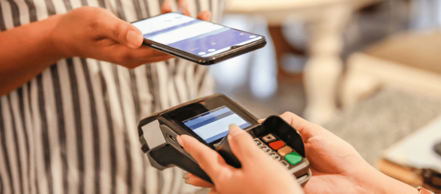 A person holds a smartphone in one hand and a credit card in the other, illustrating contactless payment methods.