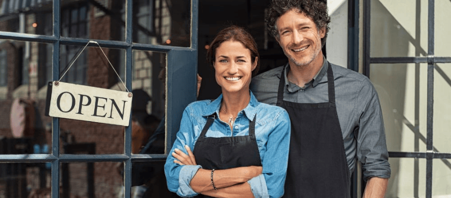 A man and woman stand in front of a business, considering SBA loans for their venture