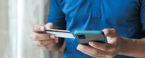 A person holding their credit card in one hand and cellphone in the other, demonstrating digital banking
