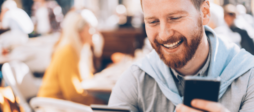 A smiling man with a beard holds a credit card, representing user satisfaction with the Farmers Bank mobile app.